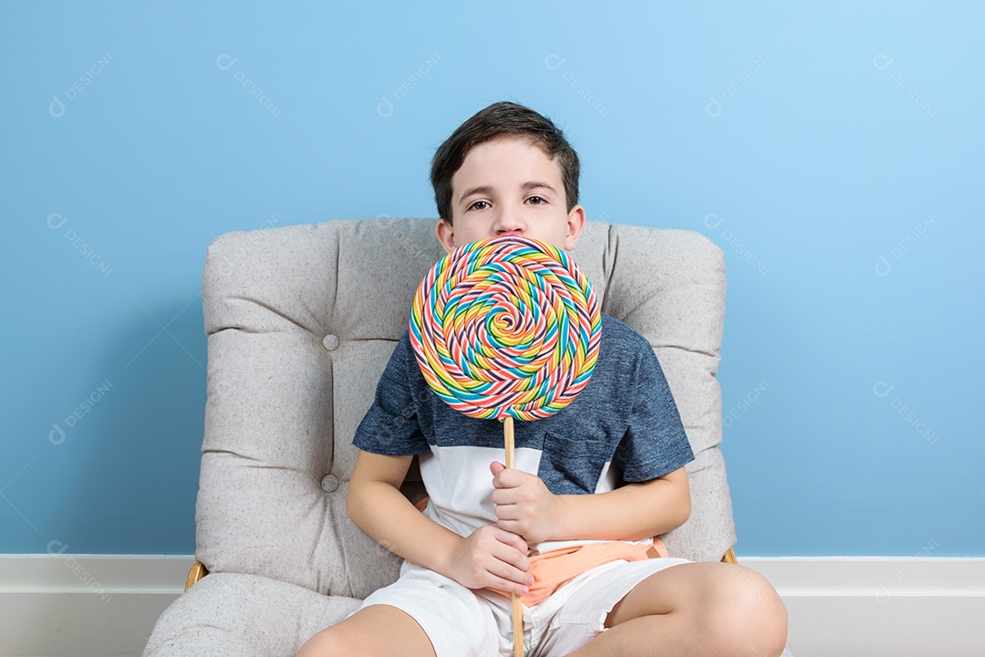 Criança brasileira de 8 anos segurando um grande pirulito colorido
