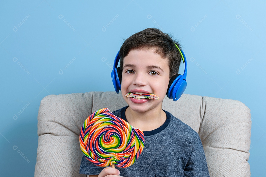 Criança de 8 anos com fone de ouvido e um pedaço de pirulito colorido