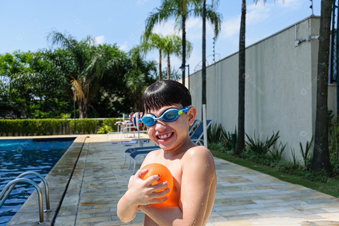 Criança sorridente de 8 anos segurando uma bomba dágua em um dia ensolarado na piscina.