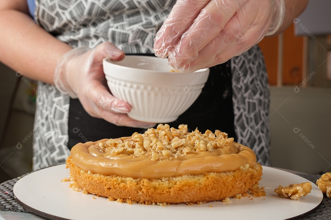 Confeiteira colocando nozes no recheio de brigadeiro de doce de leite
