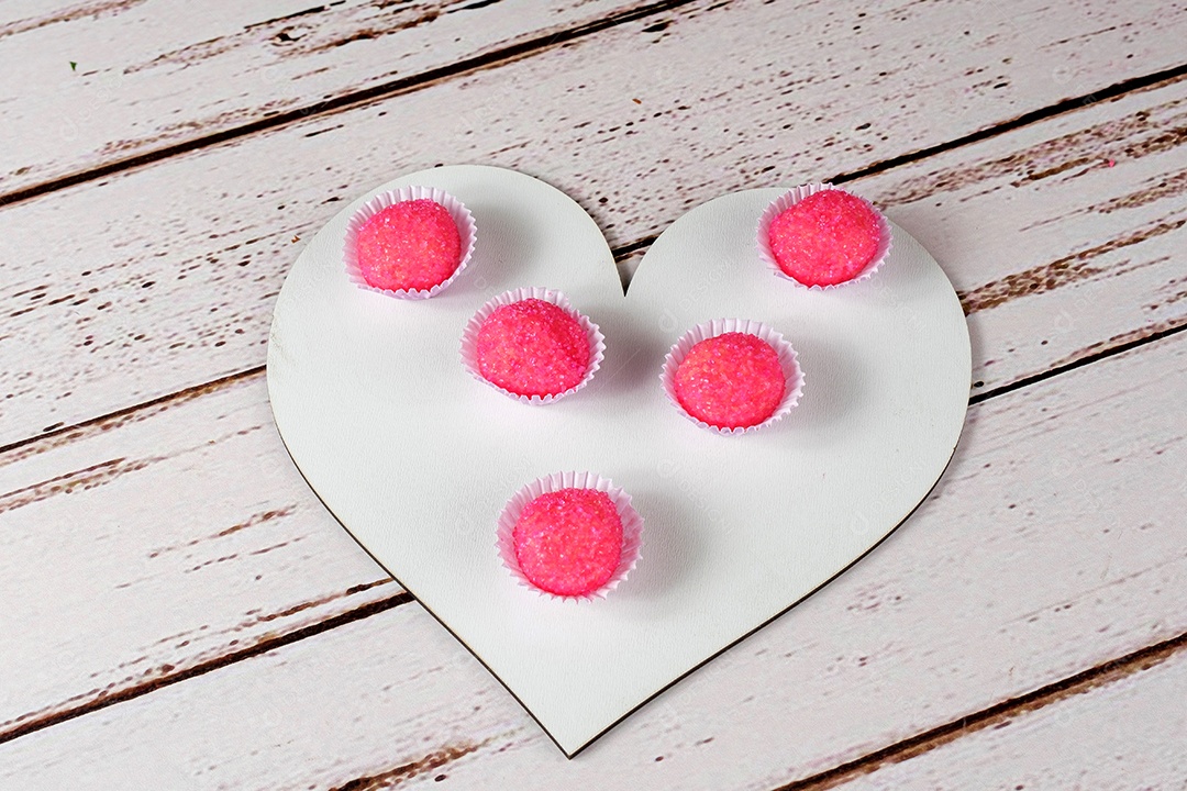 Porção de bicho de pé sobre tábua de madeira em forma de coração. Doce Tradicional Brasileiro