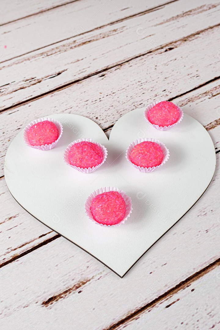 Porção de bicho de pe sobre tábua de madeira em forma de coração. Doce Tradicional Brasileiro