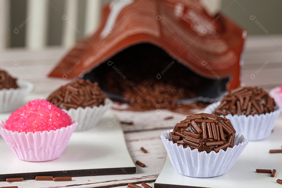 Brigadeiros e bichos de pé em pratos em formato de coração ao lado de um pacote de chocolate granulado