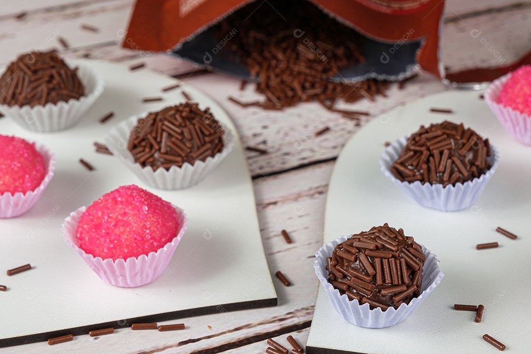 Brigadeiros e bichos de pé em pratos em formato de coração ao lado de um pacote de chocolate granulado