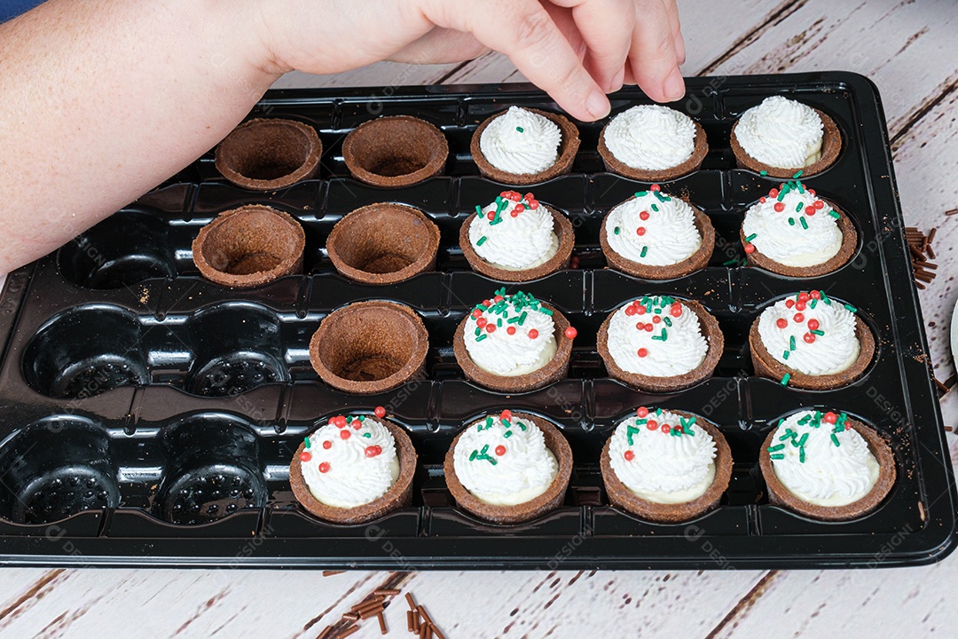 Confeiteiro decorando as mini tortas com granulados coloridos