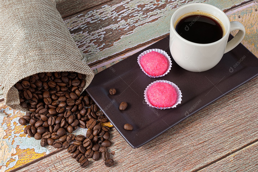 Grãos de café ao lado de brigadeiros bicho de pe e uma xícara de café.