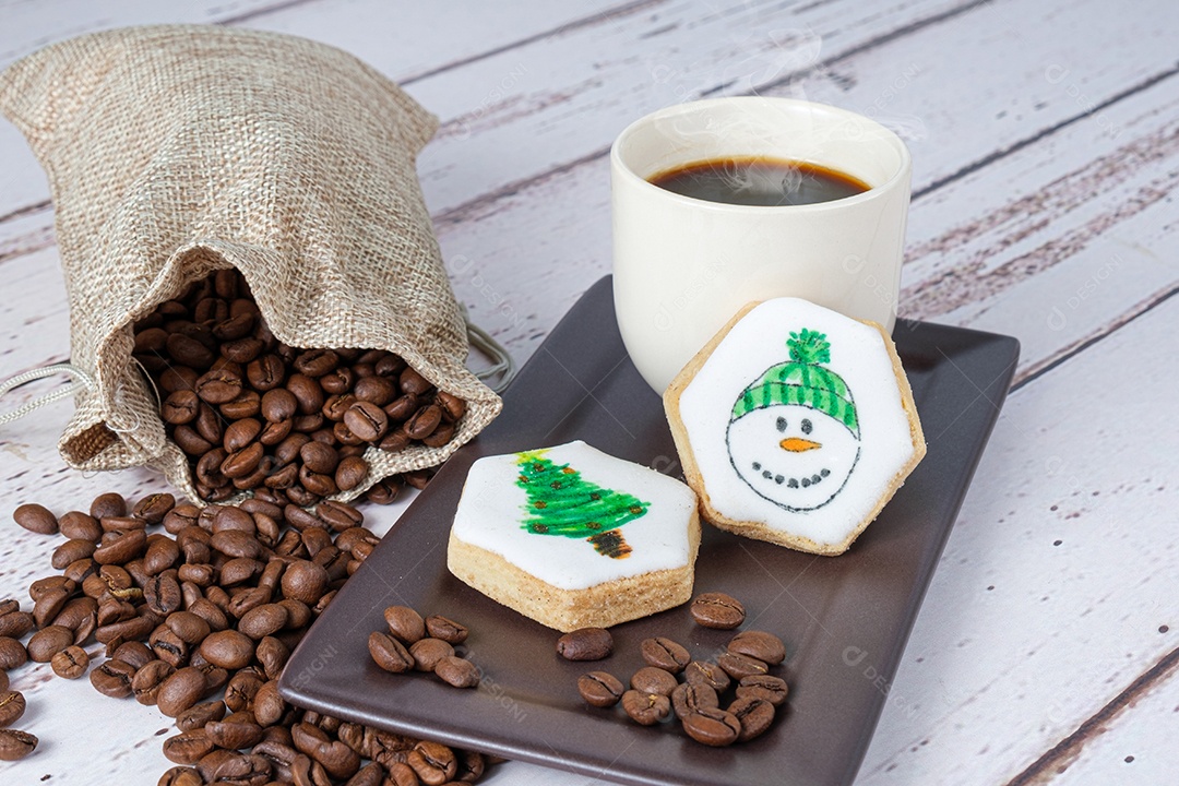 Biscoitos amanteigados com tema natalino ao lado de grãos de café e xícara.