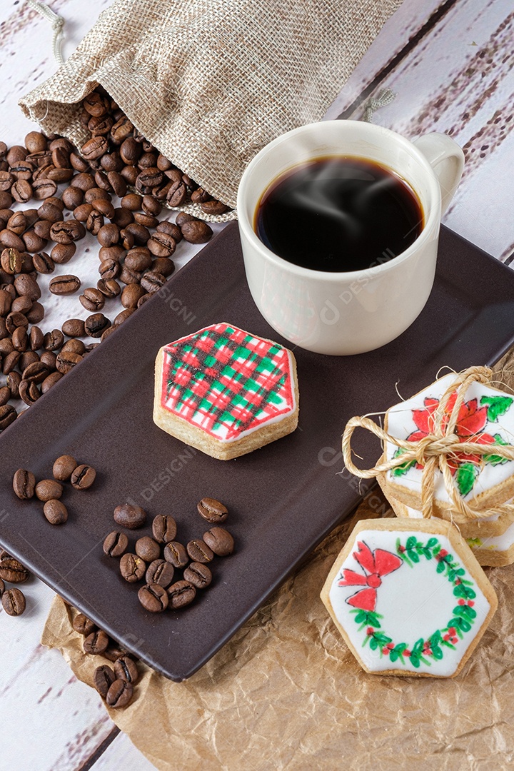 Biscoitos amanteigados com tema natalino ao lado de grãos de café e xícara.