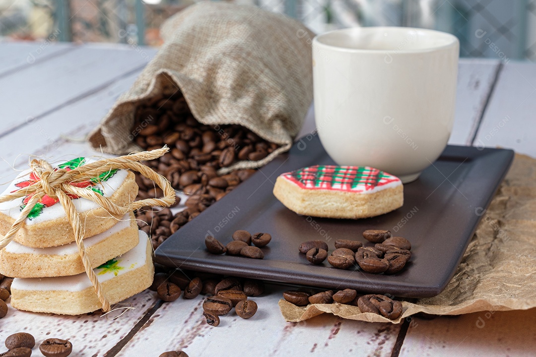 Biscoitos amanteigados com tema natalino ao lado de grãos de café e xícara.