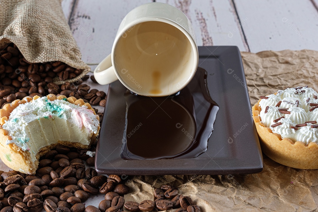 Mini torta de ganache de chocolate branco com picadinho, ao lado de um copo de café virado sobre papel pardo