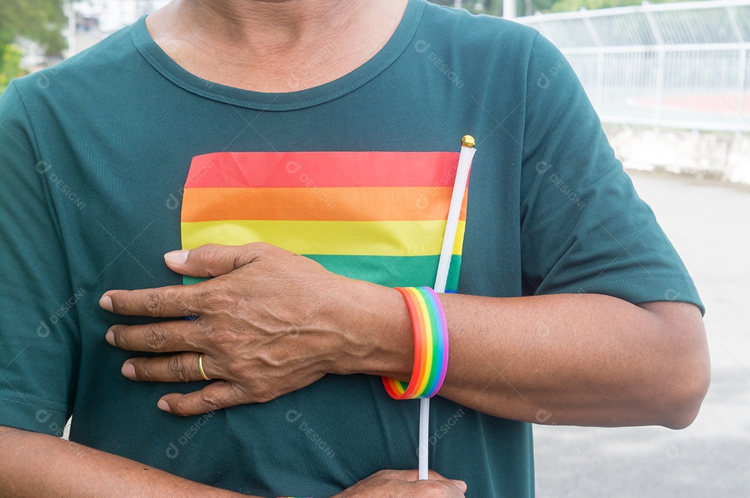 Gay asiático ou tailandês em pé e sorrindo com a bandeira do arco-íris em seu