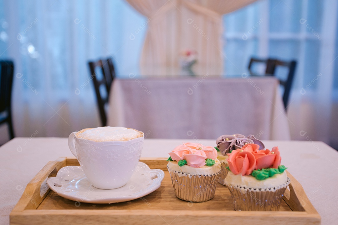 Bandeja de cupcake decorados e xícara de cappuccino