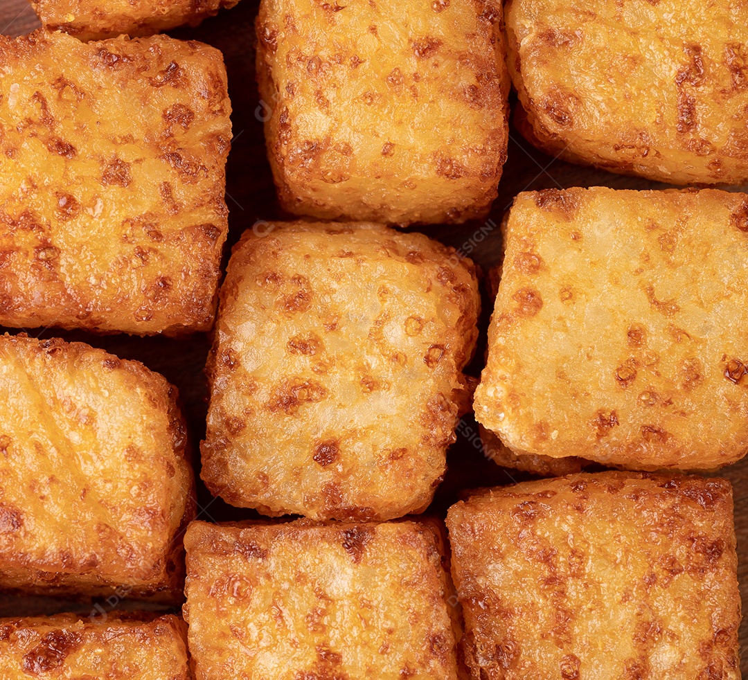 Dado de tapioca, comida típica do nordeste brasileiro com calda de pimenta malagueta sobre mesa de madeira.