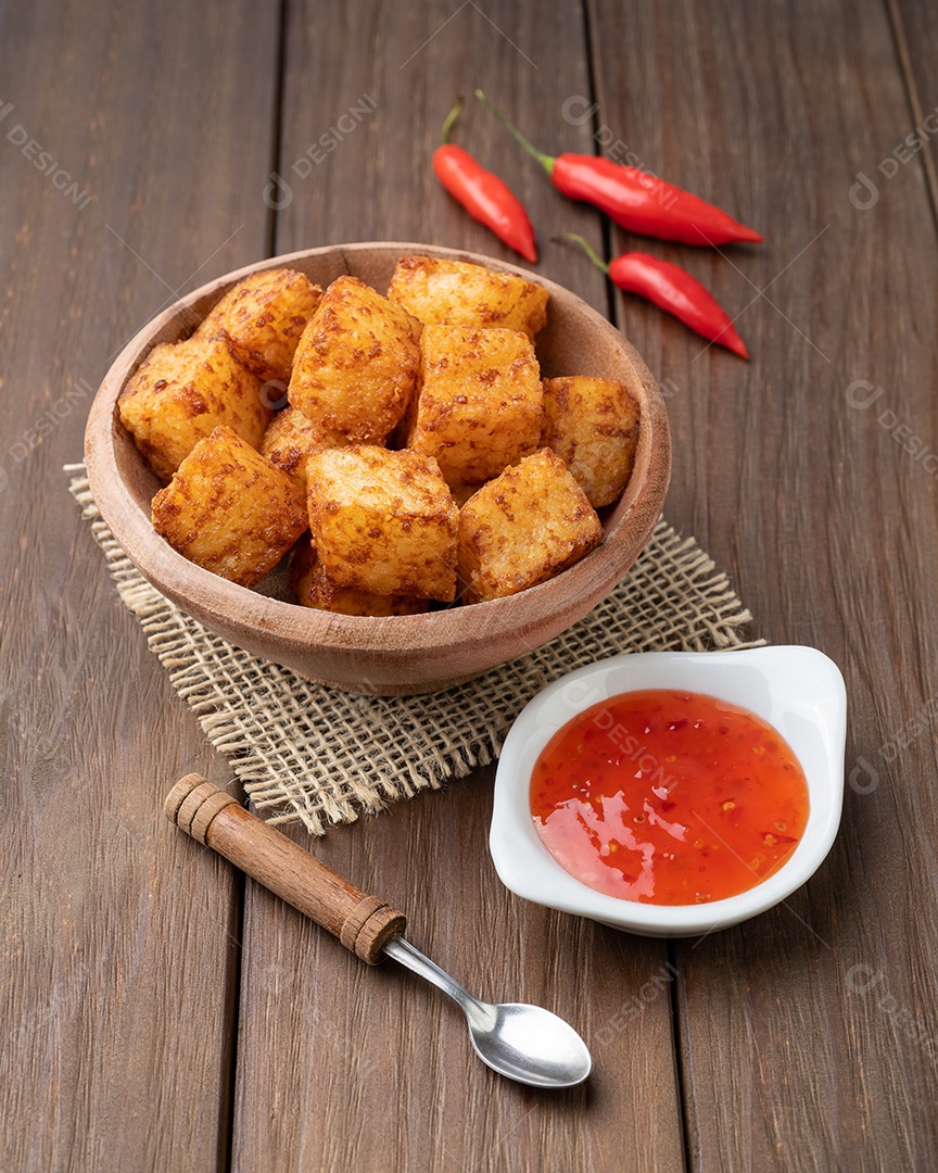 Dado de tapioca, comida típica do nordeste brasileiro com calda de pimenta malagueta sobre mesa de madeira.
