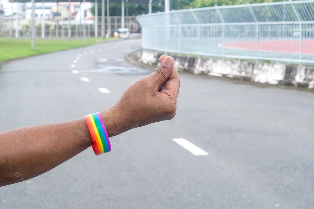 Mão usando arco-íris ou pulseira com símbolo lgbtq+ se estendendo no ar com um mini símbolo