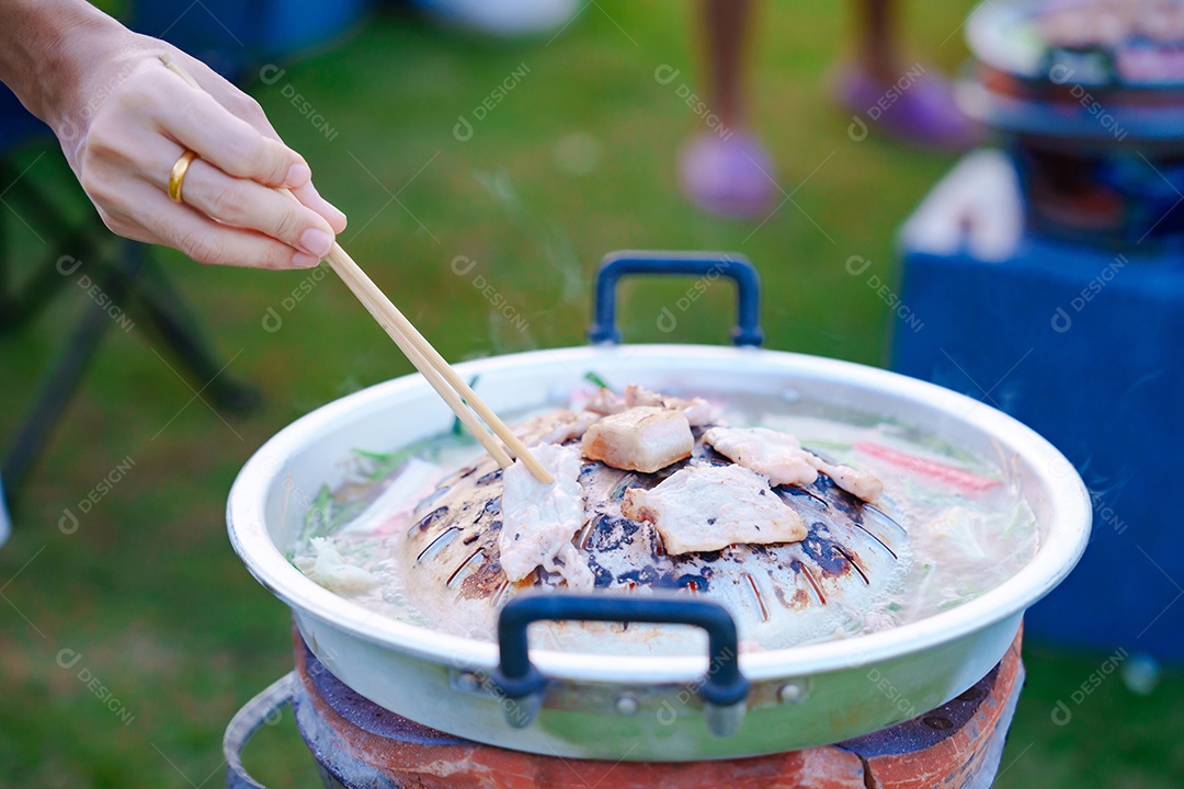 Carne de porco grelhada à mão ou com legumes e sopa na frigideira quente, festa de grupo de amigos e gangue contra a natureza ao ar livre. O estilo tradicional de churrasco tailandês é famoso na Tailândia