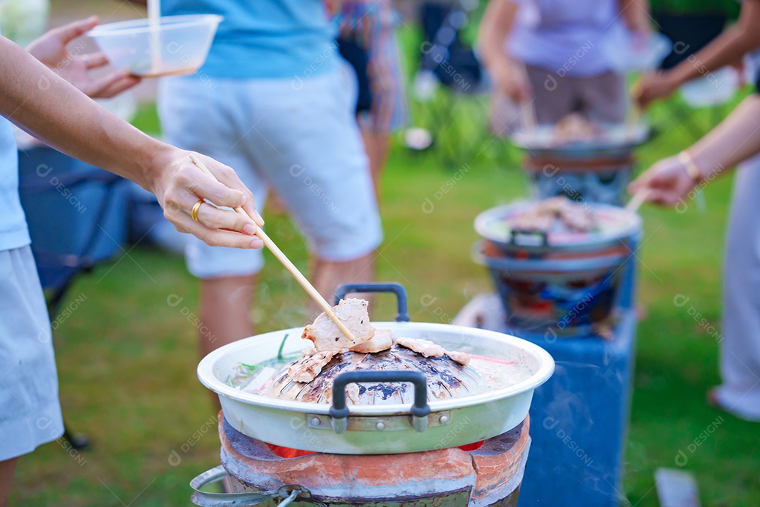 Carne de porco grelhada à mão ou com legumes e sopa na frigideira quente, festa de grupo de amigos e gangue contra a natureza ao ar livre. O estilo tradicional de churrasco tailandês é famoso na Tailândia