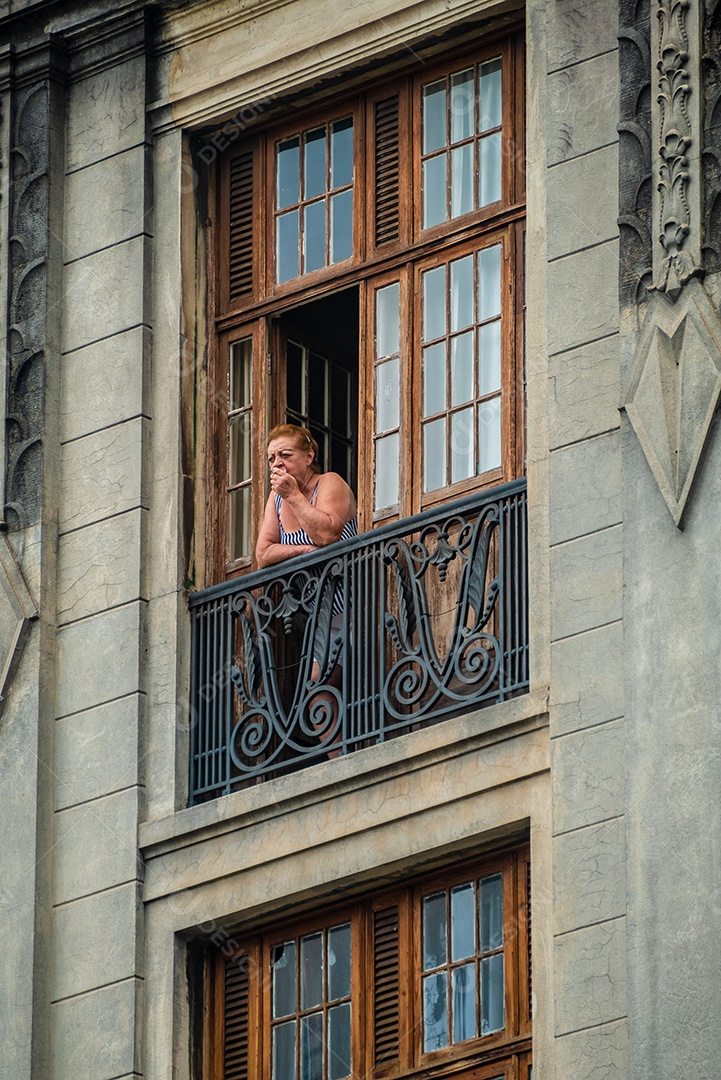Mulher fumando na janela de um apartamento