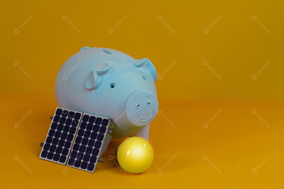 Cofrinho, lâmpada amarela e painel de energia solar fotovoltaica isolado em fundo amarelo.