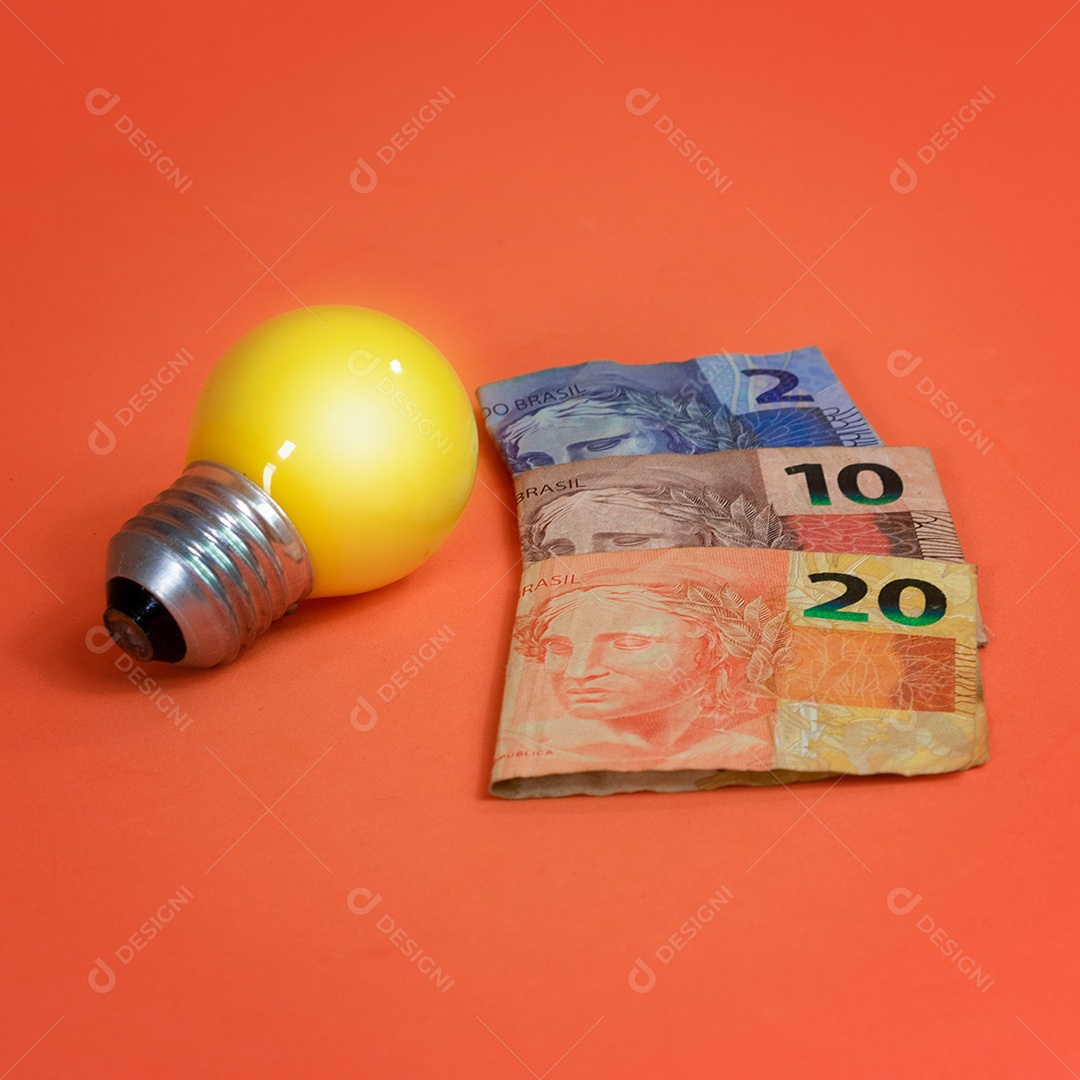 Dinheiro brasileiro e lâmpada isolados em fundo laranja. Imagem de crises de energia leve.