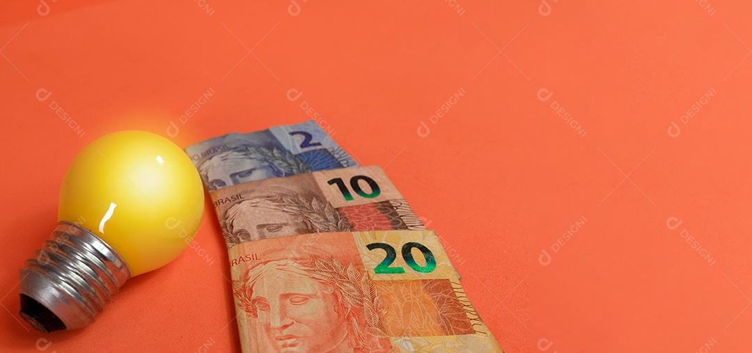 Dinheiro brasileiro e lâmpada isolados em fundo laranja. Imagem de crises de energia leve.