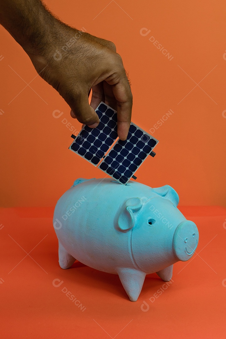 Colocando painel solar fotovoltaico no cofrinho isolado em fundo laranja.