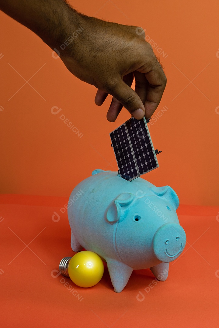 Colocando painel solar fotovoltaico no cofrinho isolado em fundo laranja.