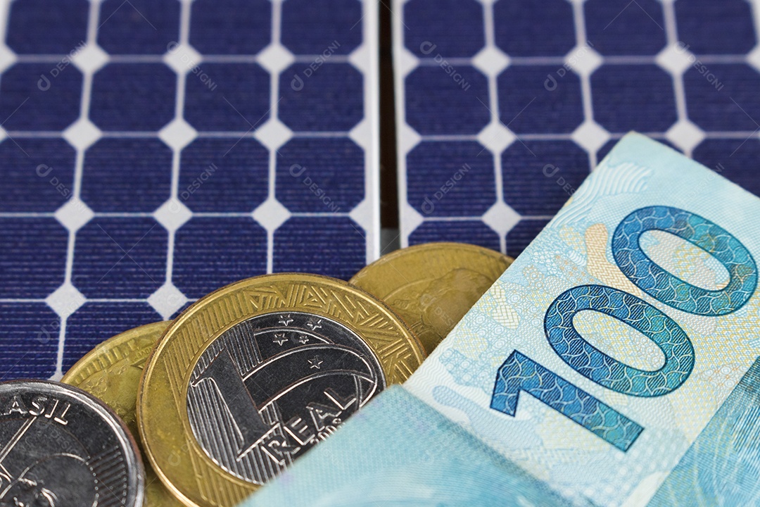 Notas e moedas brasileiras em cima de um painel solar