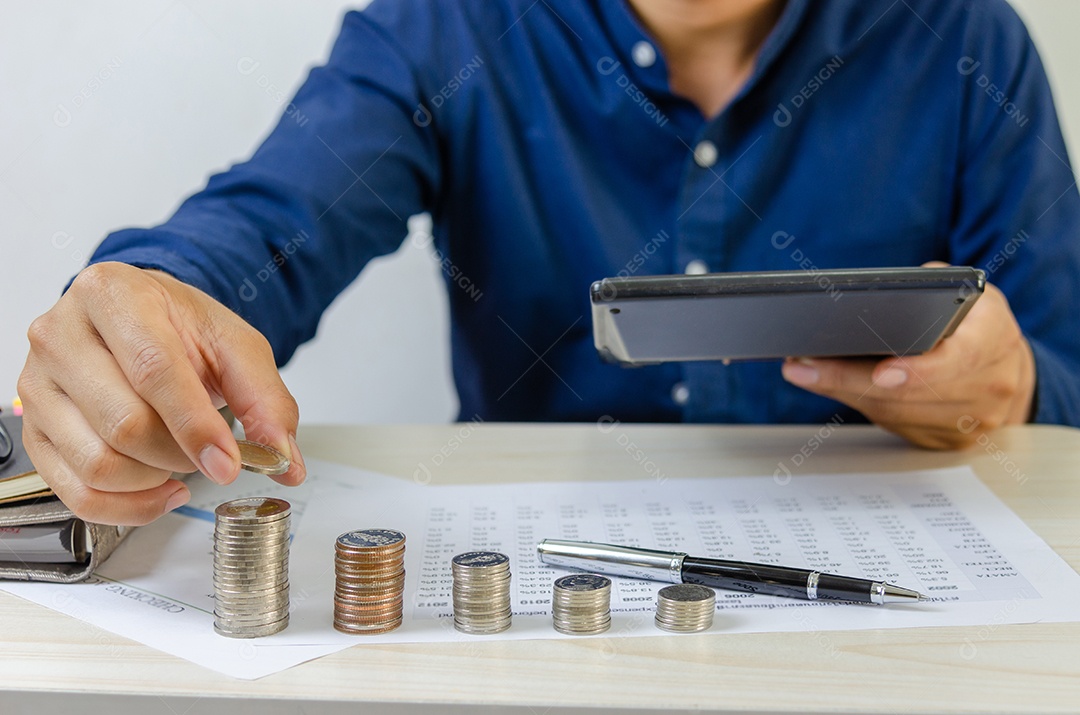 Empresário, segurando a pilha de moedas na mesa. Investimento financeiro bancário