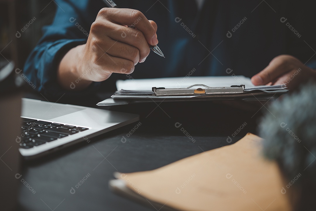 Homem de negócios lendo papel de acordo antes de assinar documento com caneta de uso no trabalho.