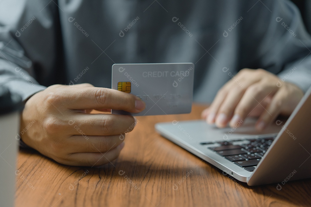 Homem segurando o cartão de crédito disponível com o computador portátil