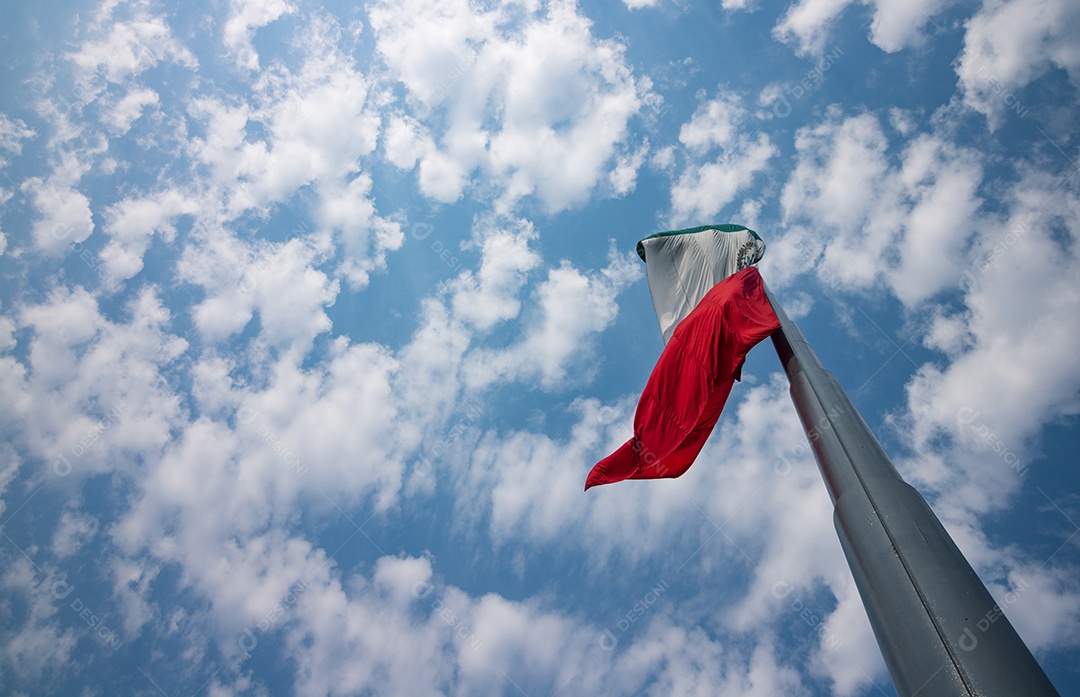 Bandeira mexicana tremulando sobre um céu nublado.