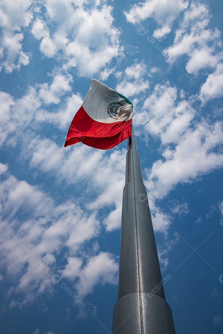 Bandeira mexicana tremulando sobre um céu nublado.