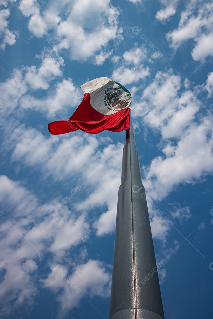 Bandeira mexicana tremulando sobre um céu nublado.