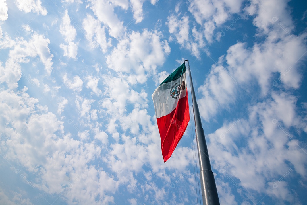 Bandeira mexicana tremulando sobre um céu nublado.