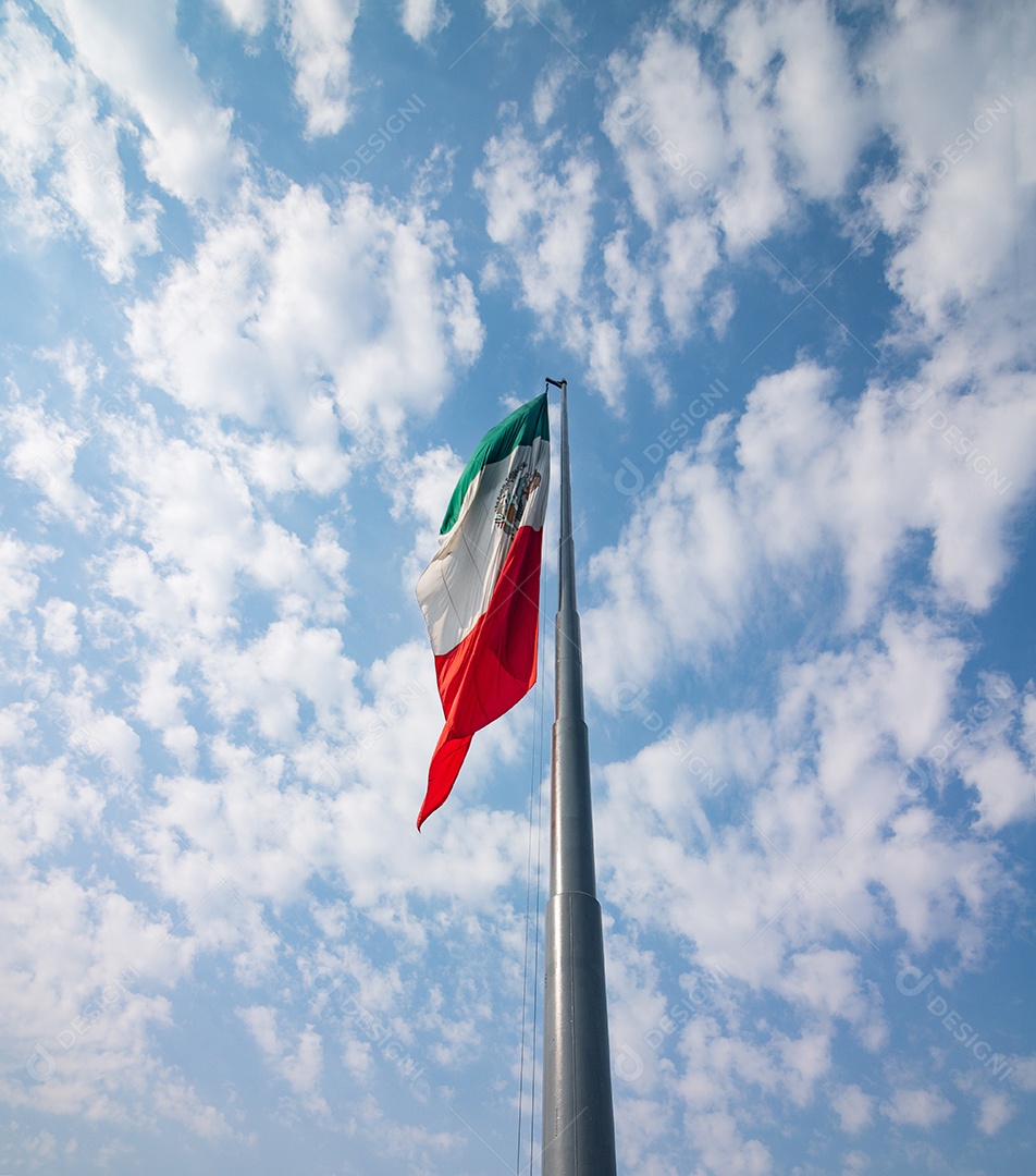 Bandeira mexicana tremulando sobre um céu nublado.