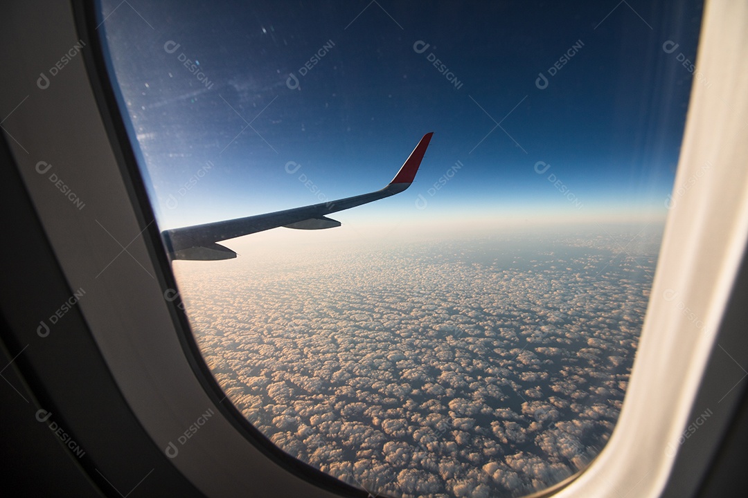 Avião de janela de exibição de viagem com montanhas e nuvens ao fundo.