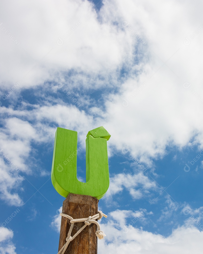 Madeira da letra U na frente do céu azul da nuvem