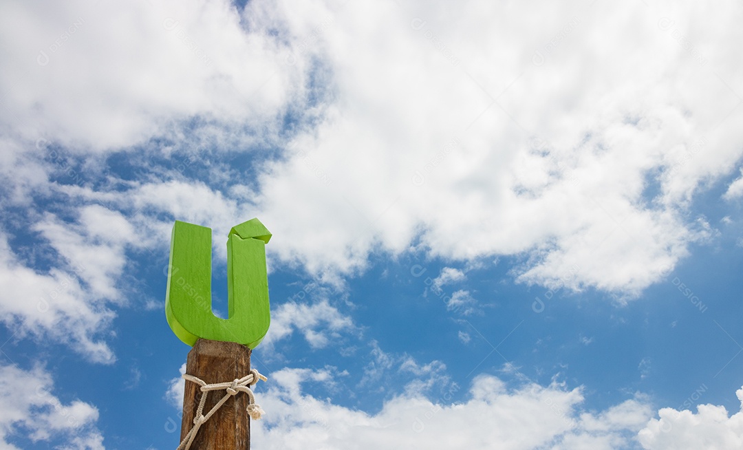 Madeira da letra U na frente do céu azul da nuvem
