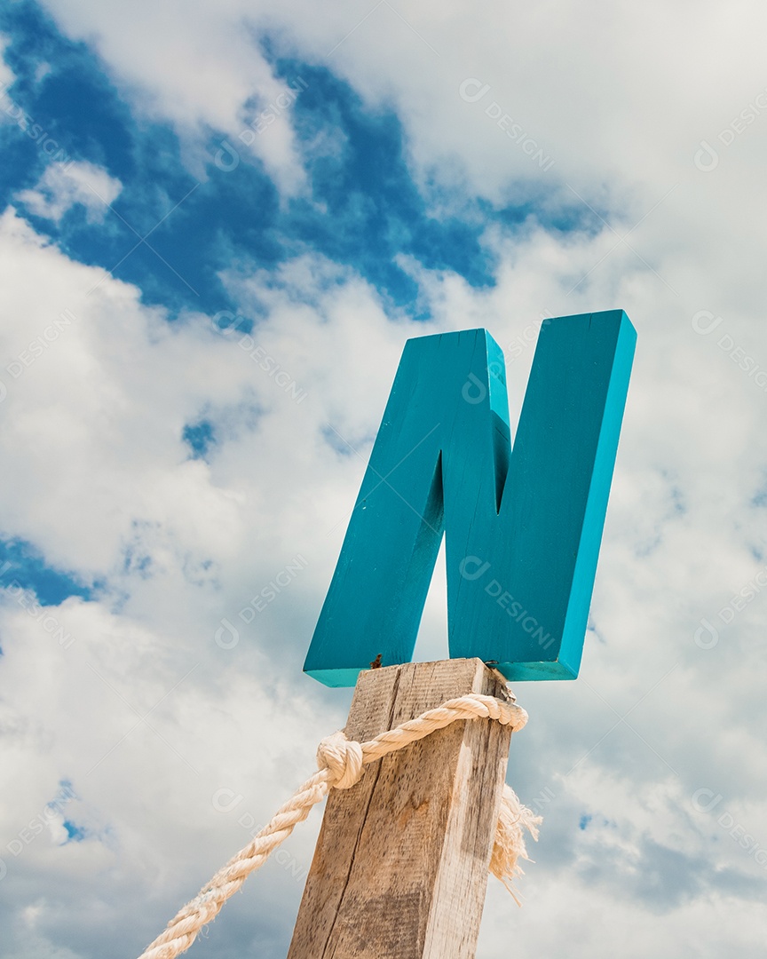 Madeira da letra N na frente do céu azul da nuvem