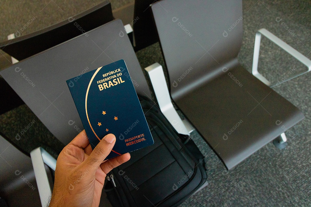 Segurando um passaporte brasileiro, mochila no fundo.