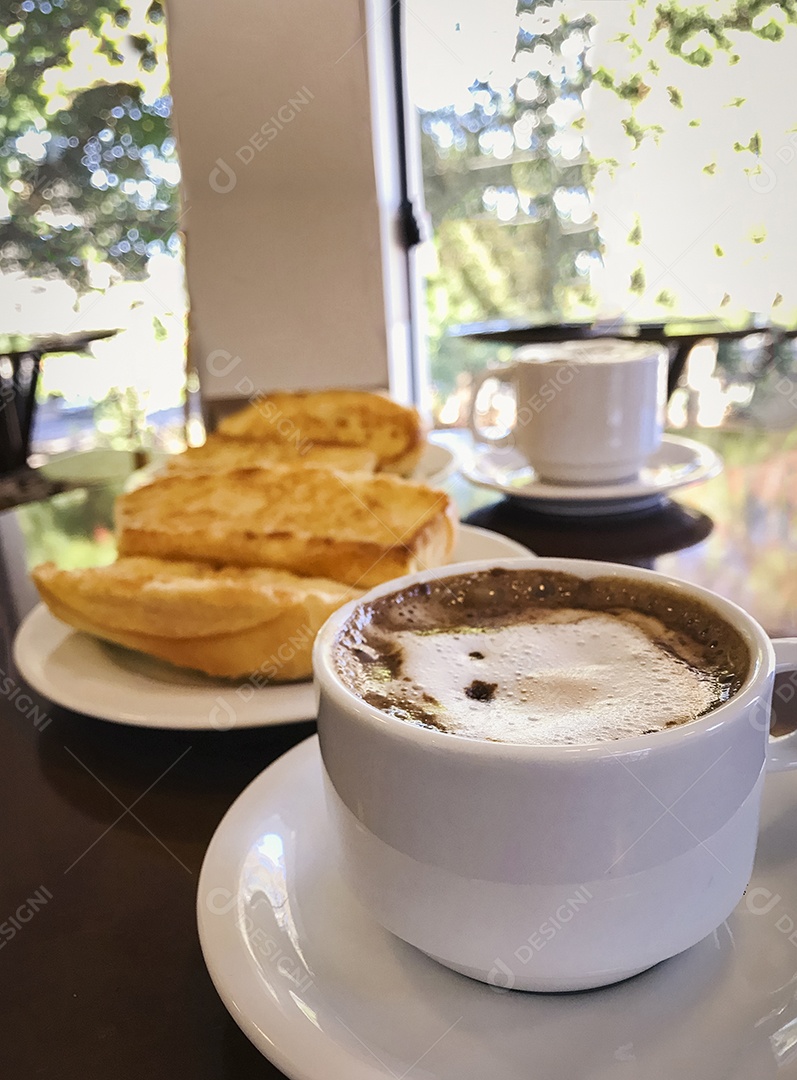 Pão torrado com manteiga na chapa e capuccino na mesa de madeira. Café da Manhã