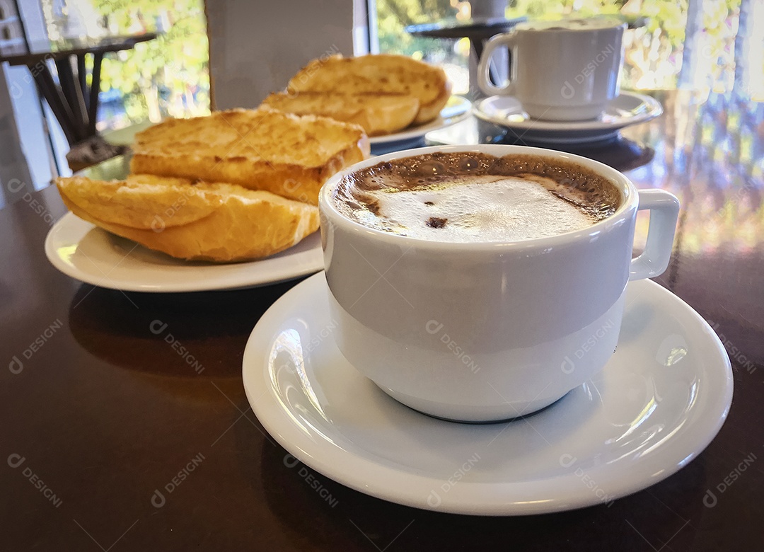 Pão torrado com manteiga na chapa e capuccino na mesa de madeira. Café da Manhã