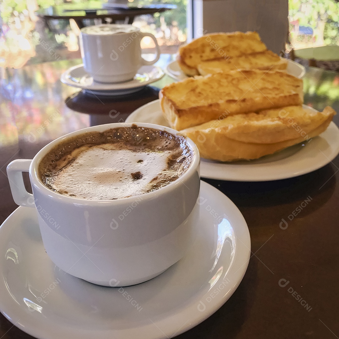 Pão torrado com manteiga na chapa e capuccino na mesa de madeira. Café da Manhã