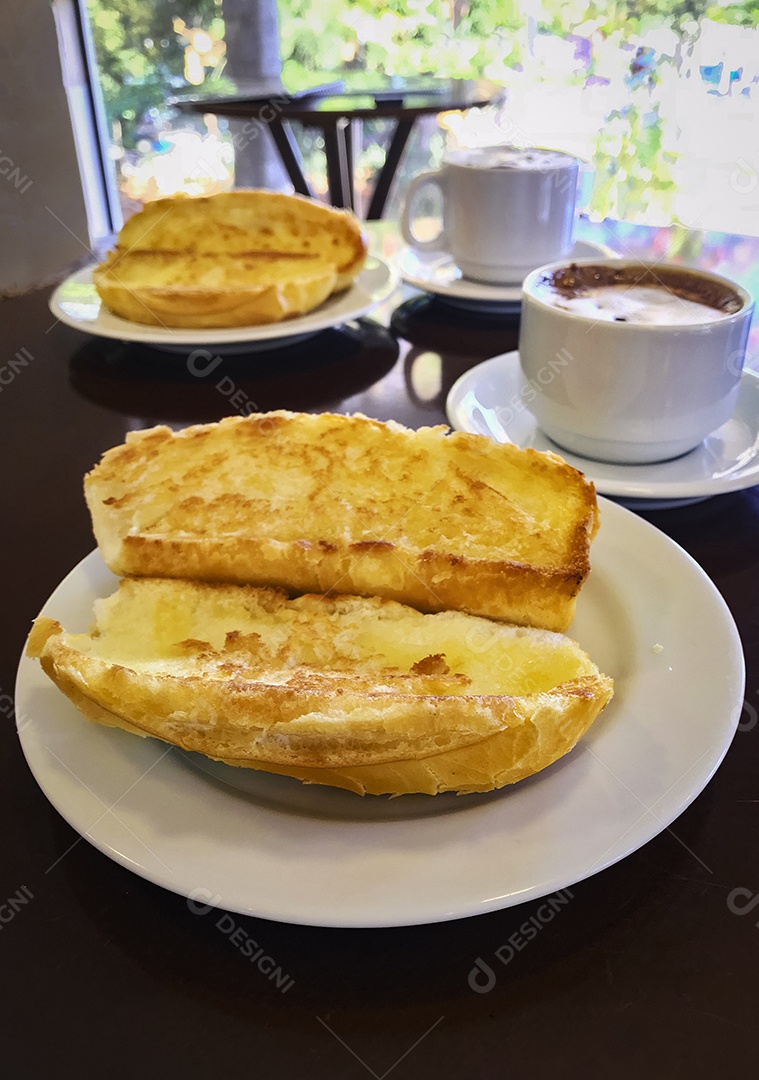 Pão torrado com manteiga na chapa e capuccino na mesa de madeira. Café da Manhã