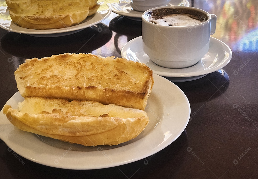 Pão torrado com manteiga na chapa e capuccino na mesa de madeira. Café da Manhã