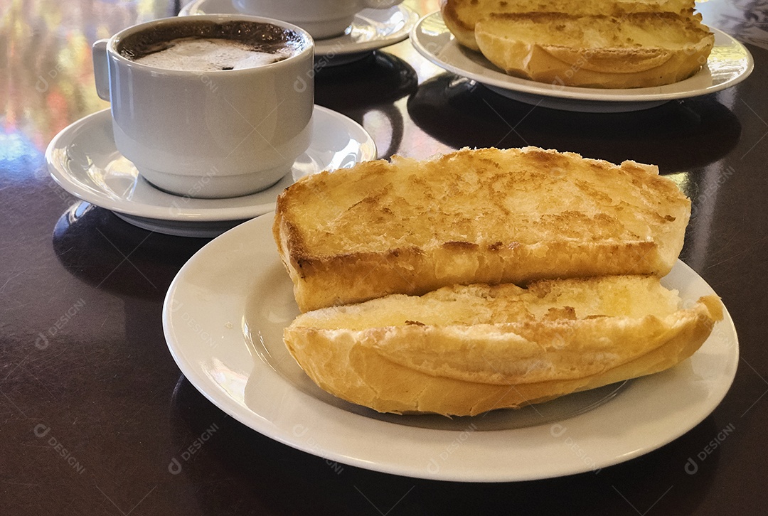 Pão torrado com manteiga na chapa e capuccino na mesa de madeira. Café da Manhã