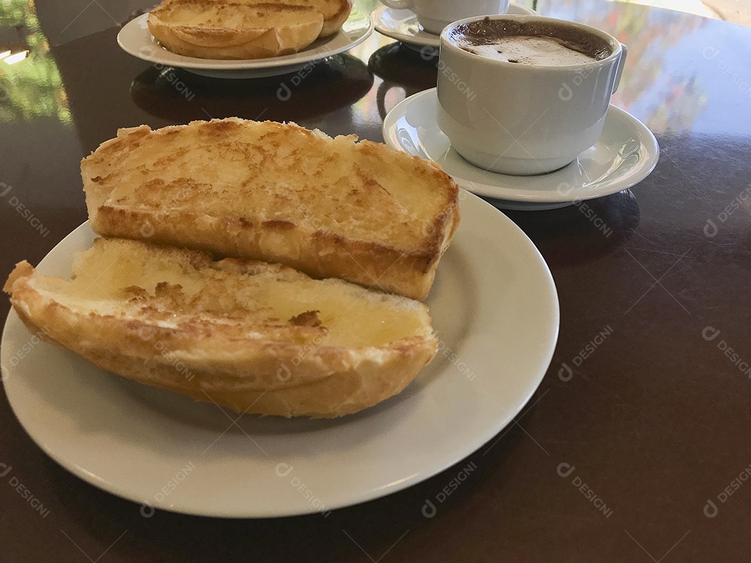 Pão torrado com manteiga na chapa e capuccino na mesa de madeira. Café da Manhã