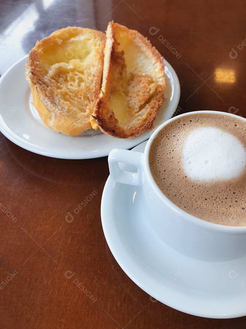 Torrada de pão com manteiga e café na mesa de madeira.
