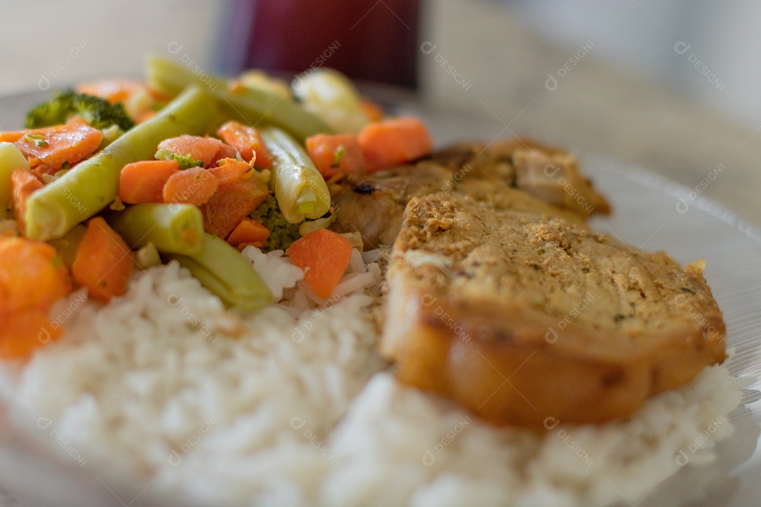 Prato com arroz e feijão e costelinha de porco na bancada.